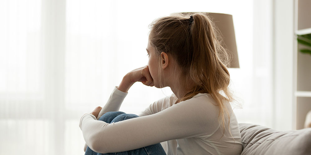 Teenage girl looking out the window upset