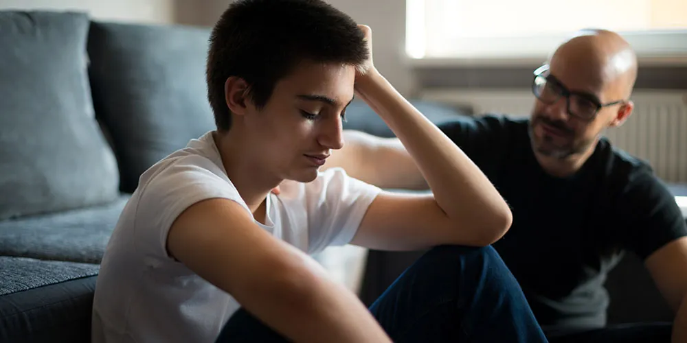 Un adolescent est réconforté par son père