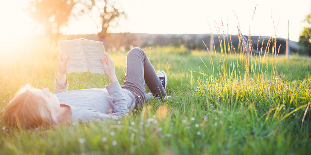 Teenager reading a book in a field